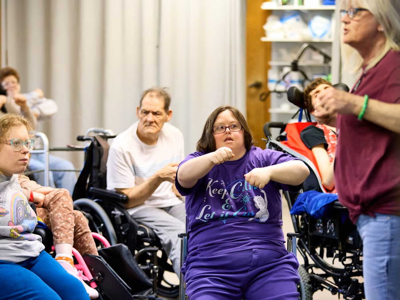 GentleBrook staff member engaging with adults with developmental disabilities in wheelchairs, highlighting inclusive care and supportive community programming